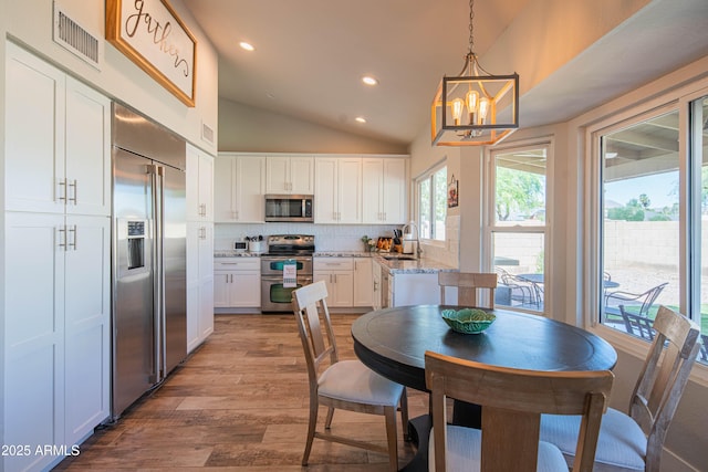 dining room with vaulted ceiling, visible vents, recessed lighting, a chandelier, and hardwood / wood-style floors