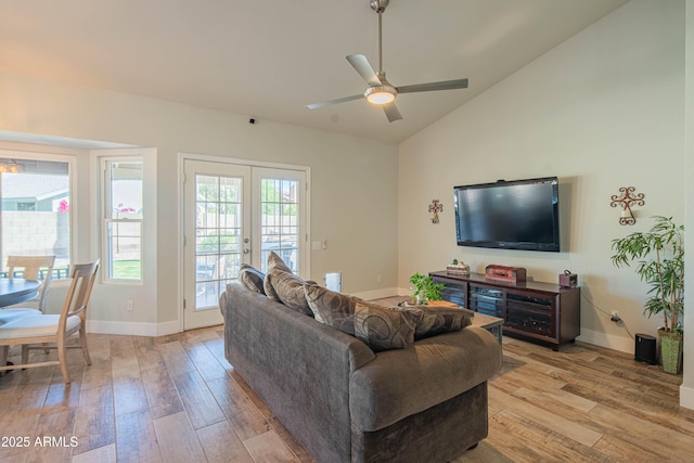 living room with french doors, baseboards, light wood-style floors, lofted ceiling, and ceiling fan
