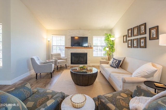 living room featuring a fireplace, lofted ceiling, wood finished floors, and baseboards