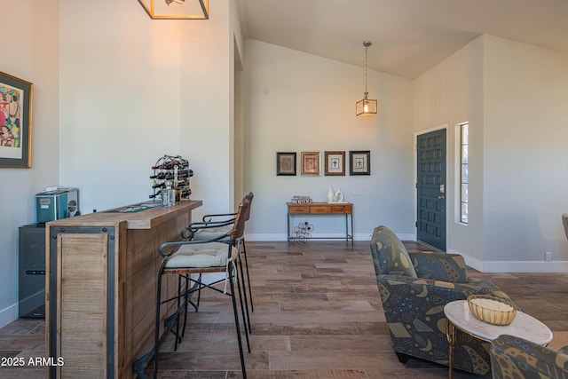 foyer entrance featuring baseboards, high vaulted ceiling, and wood finished floors