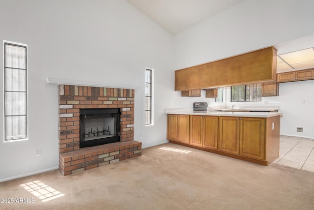 6602 W Ironwood Dr, Glendale, AZ 85302 - kitchen with high vaulted ceiling, a peninsula, brown cabinets, a fireplace, and light countertops