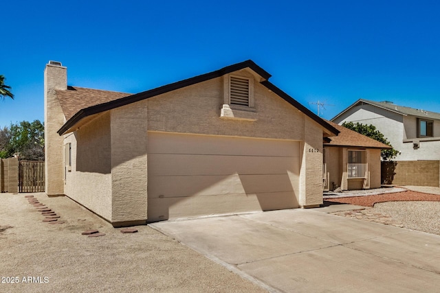 6602 W Ironwood Dr, Glendale, AZ 85302 - view of front of home featuring concrete driveway, an attached garage, a chimney, and stucco siding