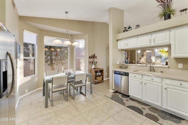 kitchen featuring decorative light fixtures, white cabinetry, stainless steel appliances, and vaulted ceiling