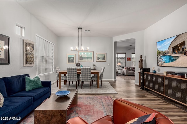 living room featuring an inviting chandelier, baseboards, visible vents, and wood finished floors