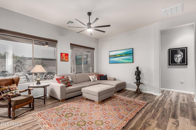 living area featuring a ceiling fan, visible vents, baseboards, and wood finished floors