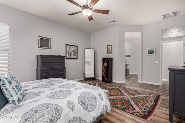 bedroom with a ceiling fan, wood finished floors, visible vents, and baseboards