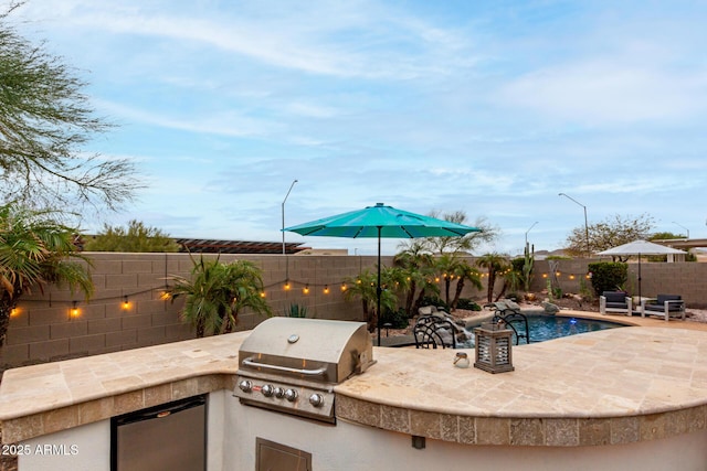 view of patio featuring exterior kitchen, a fenced in pool, a fenced backyard, and grilling area