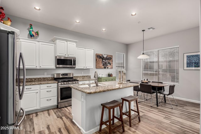 kitchen with appliances with stainless steel finishes, light wood-type flooring, a sink, and white cabinetry