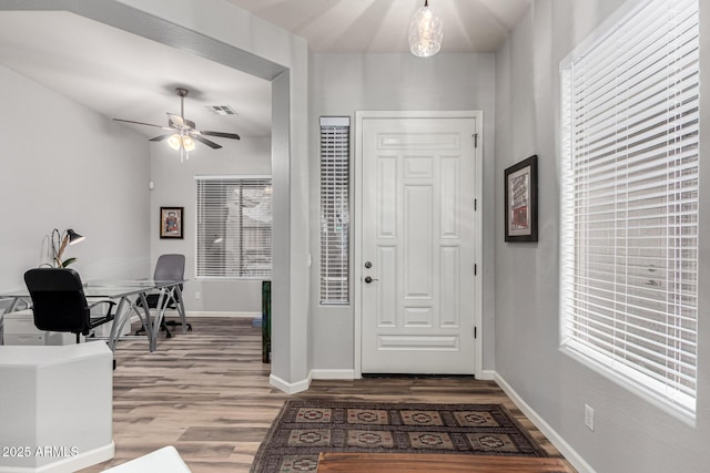 foyer entrance featuring visible vents, ceiling fan, baseboards, and wood finished floors