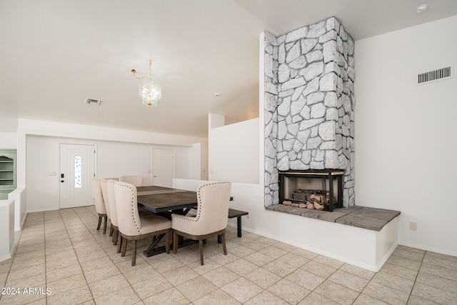 tiled dining room featuring a stone fireplace