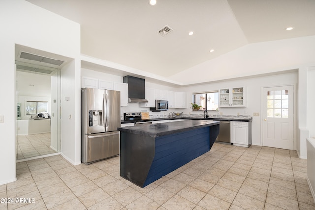 kitchen with appliances with stainless steel finishes, a kitchen island, vaulted ceiling, and white cabinets