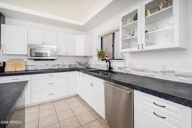 kitchen with appliances with stainless steel finishes, white cabinetry, light tile patterned floors, and sink