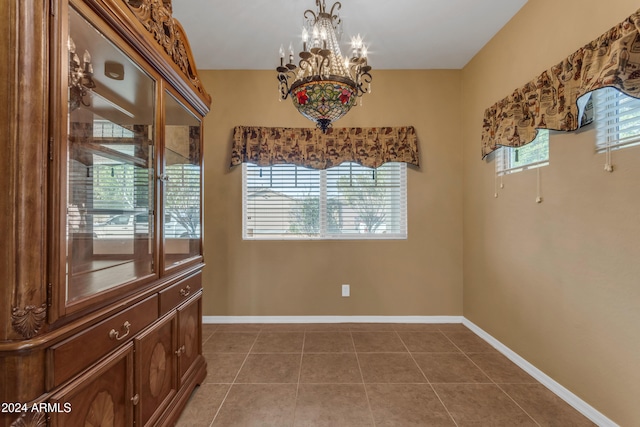 tiled spare room featuring a notable chandelier and plenty of natural light