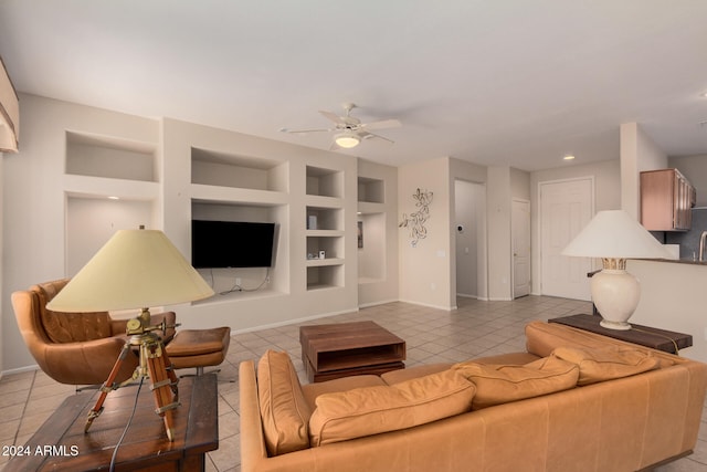 tiled living room with ceiling fan and built in shelves