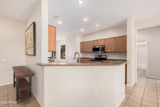 kitchen with kitchen peninsula, appliances with stainless steel finishes, sink, and light tile patterned floors