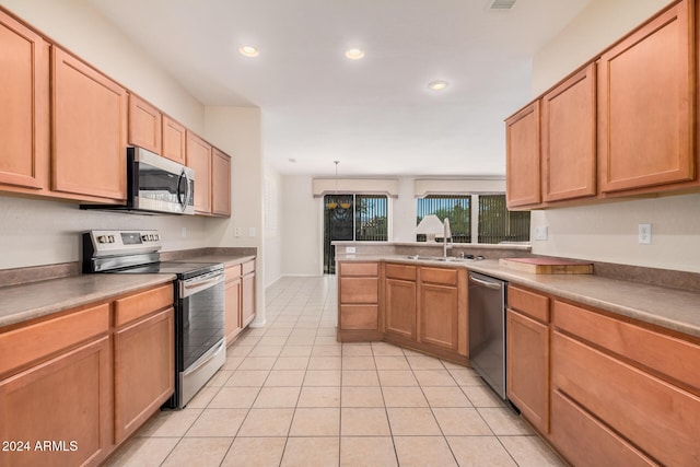 kitchen with sink, kitchen peninsula, appliances with stainless steel finishes, light tile patterned floors, and pendant lighting