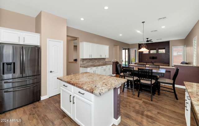 kitchen with white cabinets, stainless steel refrigerator with ice dispenser, a kitchen island, and dark wood-type flooring