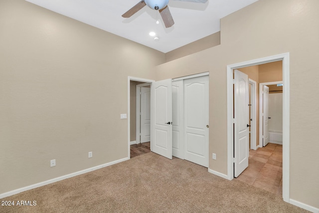 unfurnished bedroom with ceiling fan, light carpet, and a closet