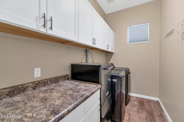 laundry room featuring cabinets, dark hardwood / wood-style floors, and washer and clothes dryer