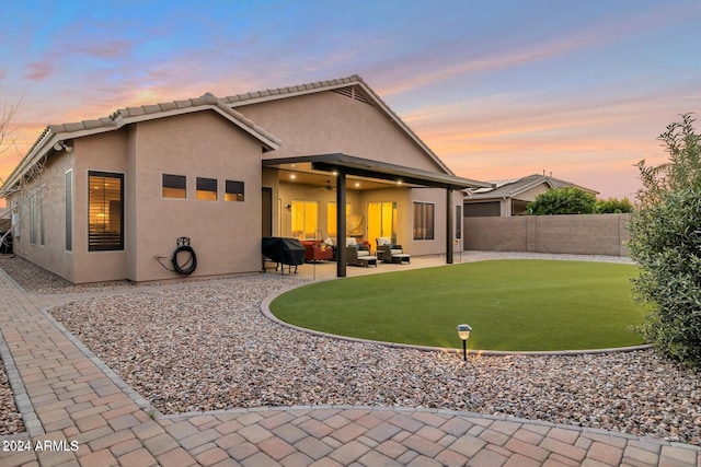 back house at dusk with outdoor lounge area and a patio area