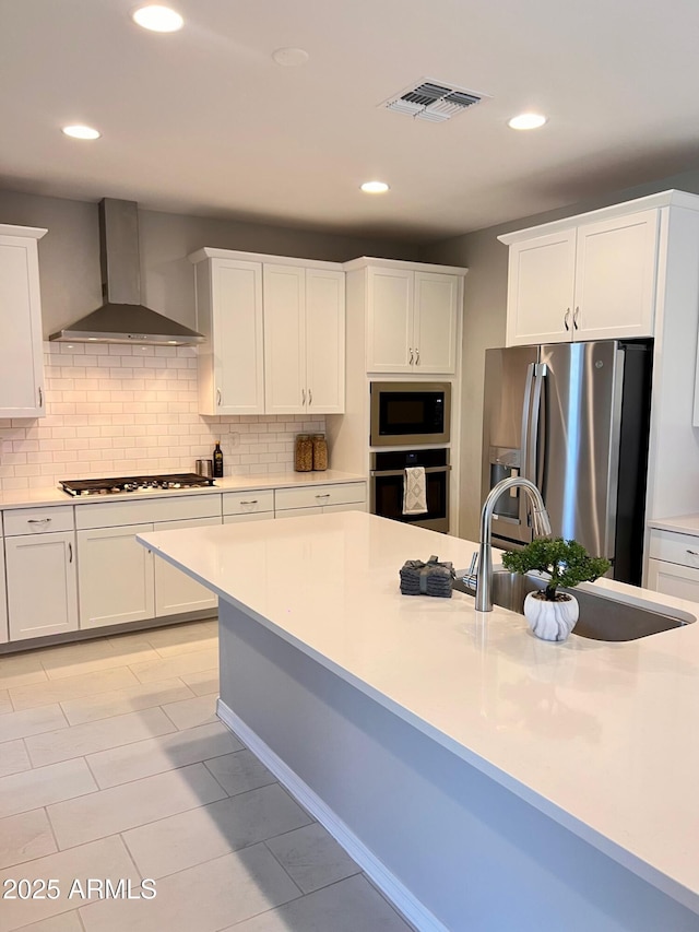 11074 W Tonto St, Avondale, AZ 85323 - kitchen featuring wall chimney range hood, a sink, stainless steel appliances, decorative backsplash, and visible vents