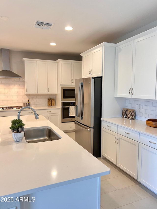 11074 W Tonto St, Avondale, AZ 85323 - kitchen featuring appliances with stainless steel finishes, a sink, light countertops, wall chimney exhaust hood, and visible vents