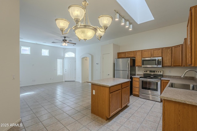 kitchen featuring sink, a center island, hanging light fixtures, light tile patterned floors, and stainless steel appliances