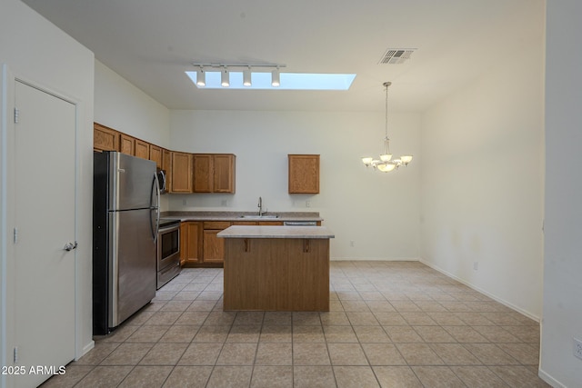 kitchen with sink, appliances with stainless steel finishes, hanging light fixtures, a skylight, and a center island