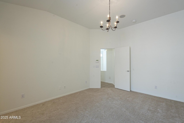 empty room with light carpet, lofted ceiling, and a chandelier