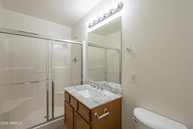 bathroom with a shower with door, vanity, and toilet