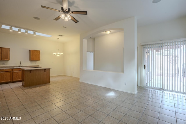 interior space with sink, hanging light fixtures, ceiling fan with notable chandelier, and light tile patterned floors