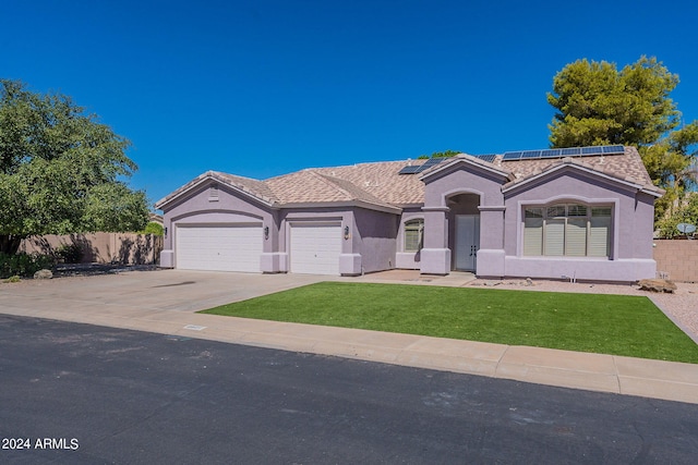 view of front of house featuring solar panels, a front yard, and a garage