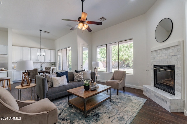 living room with ceiling fan with notable chandelier, a fireplace, and dark hardwood / wood-style flooring