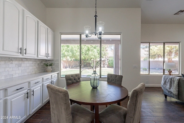 dining area featuring a chandelier, dark wood-type flooring, and a healthy amount of sunlight