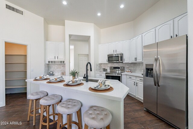 kitchen with stainless steel appliances, dark hardwood / wood-style flooring, and white cabinetry