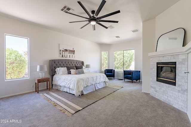 bedroom with light carpet, ceiling fan, and a fireplace