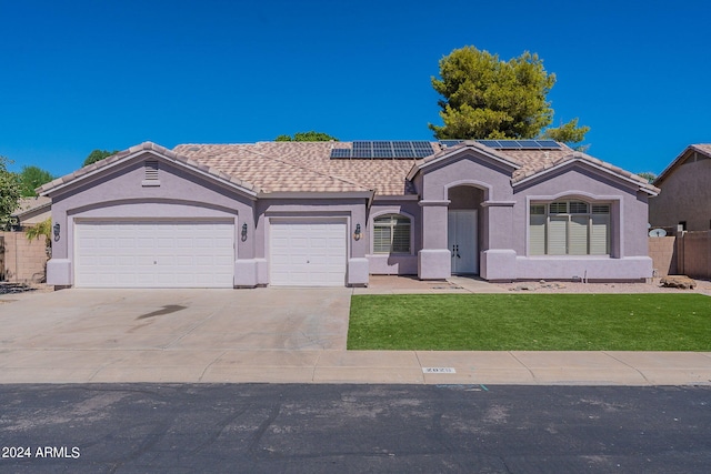 view of front of house featuring a front yard, a garage, and solar panels