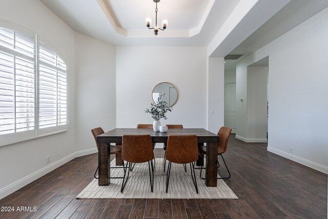 dining area featuring a tray ceiling, dark hardwood / wood-style floors, and a chandelier