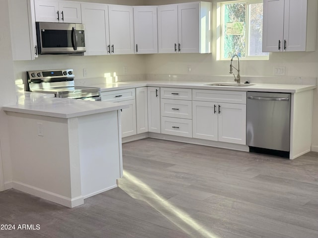 kitchen with stainless steel appliances, white cabinets, sink, and light wood-type flooring