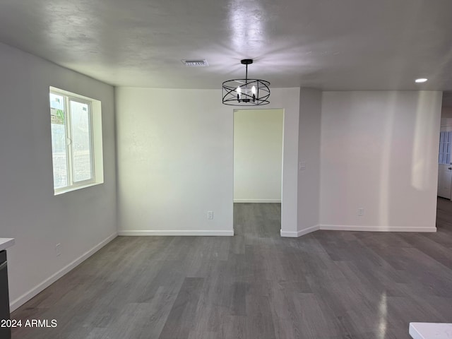 unfurnished room featuring dark hardwood / wood-style floors and an inviting chandelier