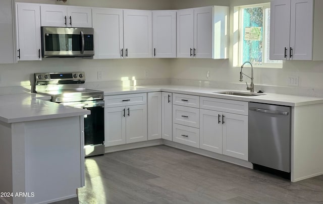 kitchen with white cabinets, light wood-type flooring, stainless steel appliances, and sink