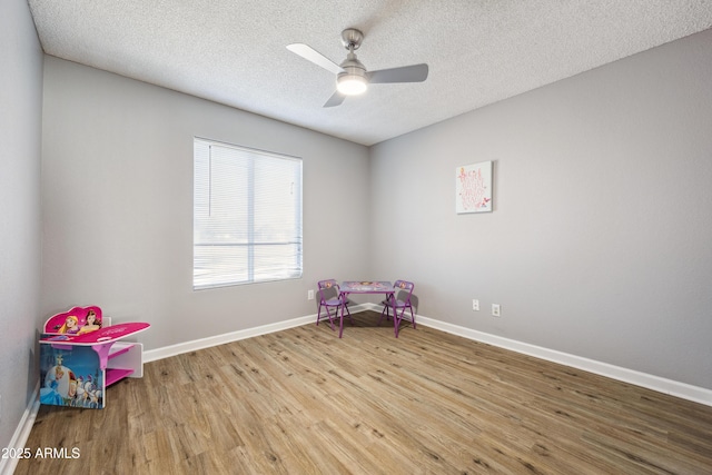 recreation room with ceiling fan, a textured ceiling, and light wood-type flooring