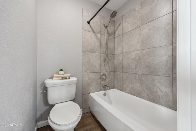 bathroom with hardwood / wood-style flooring, toilet, and tiled shower / bath combo