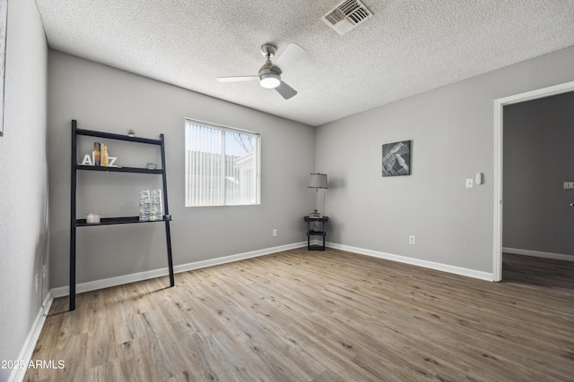 empty room featuring ceiling fan, wood-type flooring, and a textured ceiling