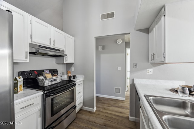 kitchen with sink, appliances with stainless steel finishes, white cabinetry, light stone countertops, and dark hardwood / wood-style flooring