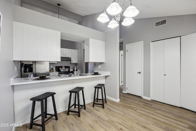 kitchen with pendant lighting, range, white cabinets, a kitchen bar, and kitchen peninsula