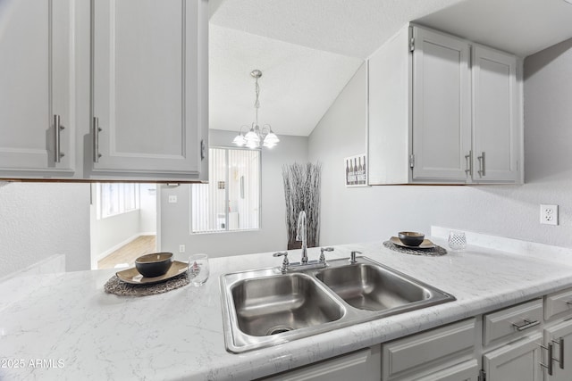 kitchen featuring gray cabinetry, sink, and vaulted ceiling