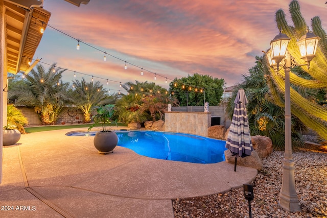 pool at dusk featuring a patio