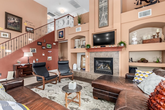 tiled living room featuring a high ceiling, built in shelves, and a fireplace