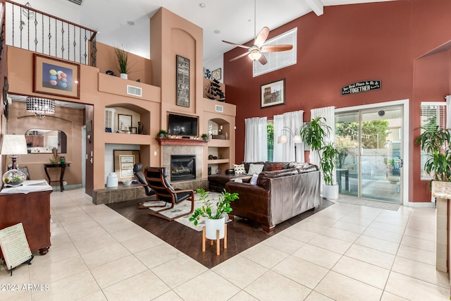 living room with a tile fireplace, beam ceiling, built in shelves, high vaulted ceiling, and ceiling fan